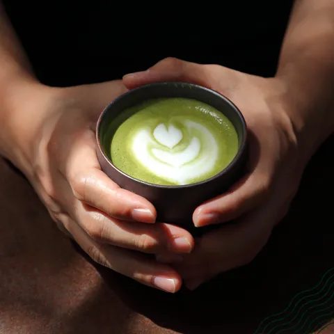 Hands holding a matcha latte, NaturaleBio organic products
