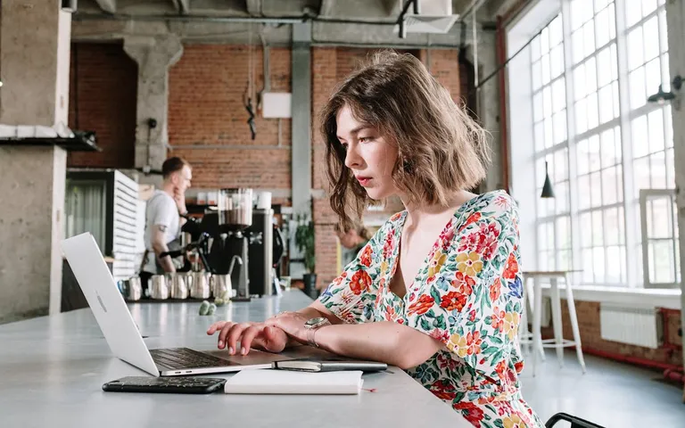 Woman working on laptop in a brick-wall industrial café