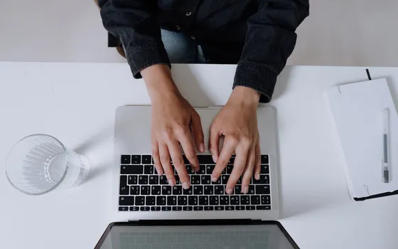 Hands typing on a laptop at a clean white desk
